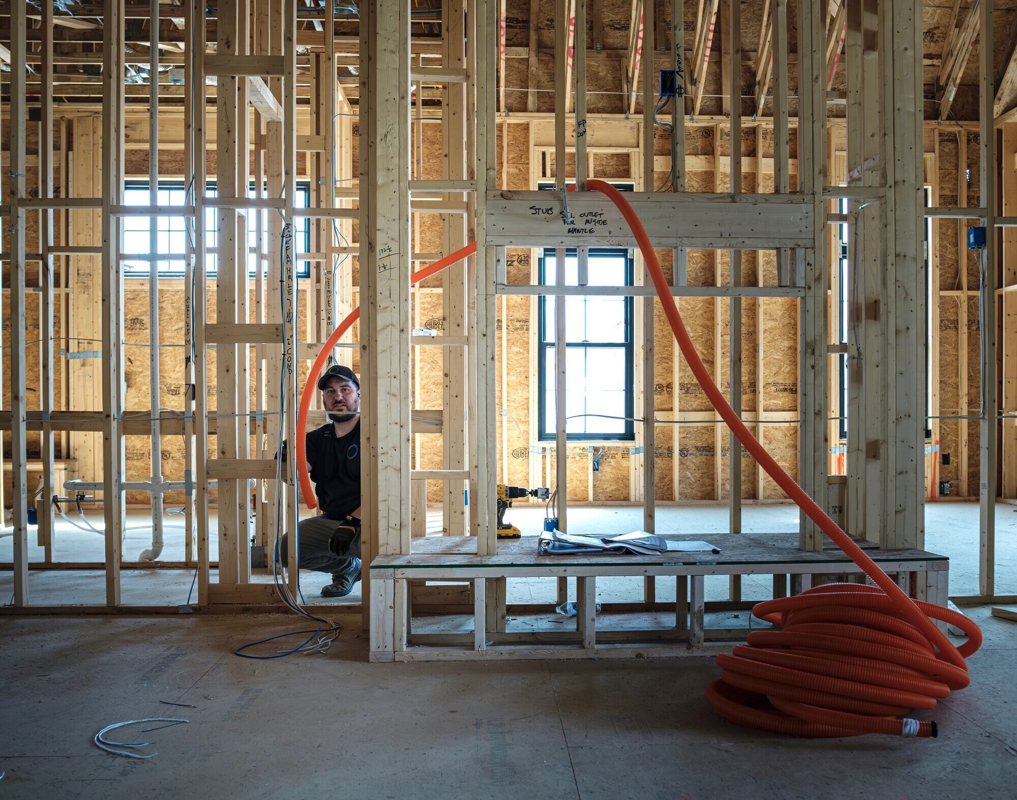 Connesso technician running low-voltage prewire through wood framing during construction