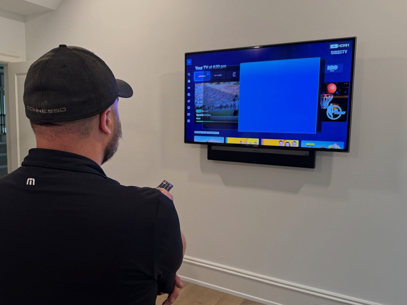 Connesso technician configuring a wall-mounted TV and soundbar