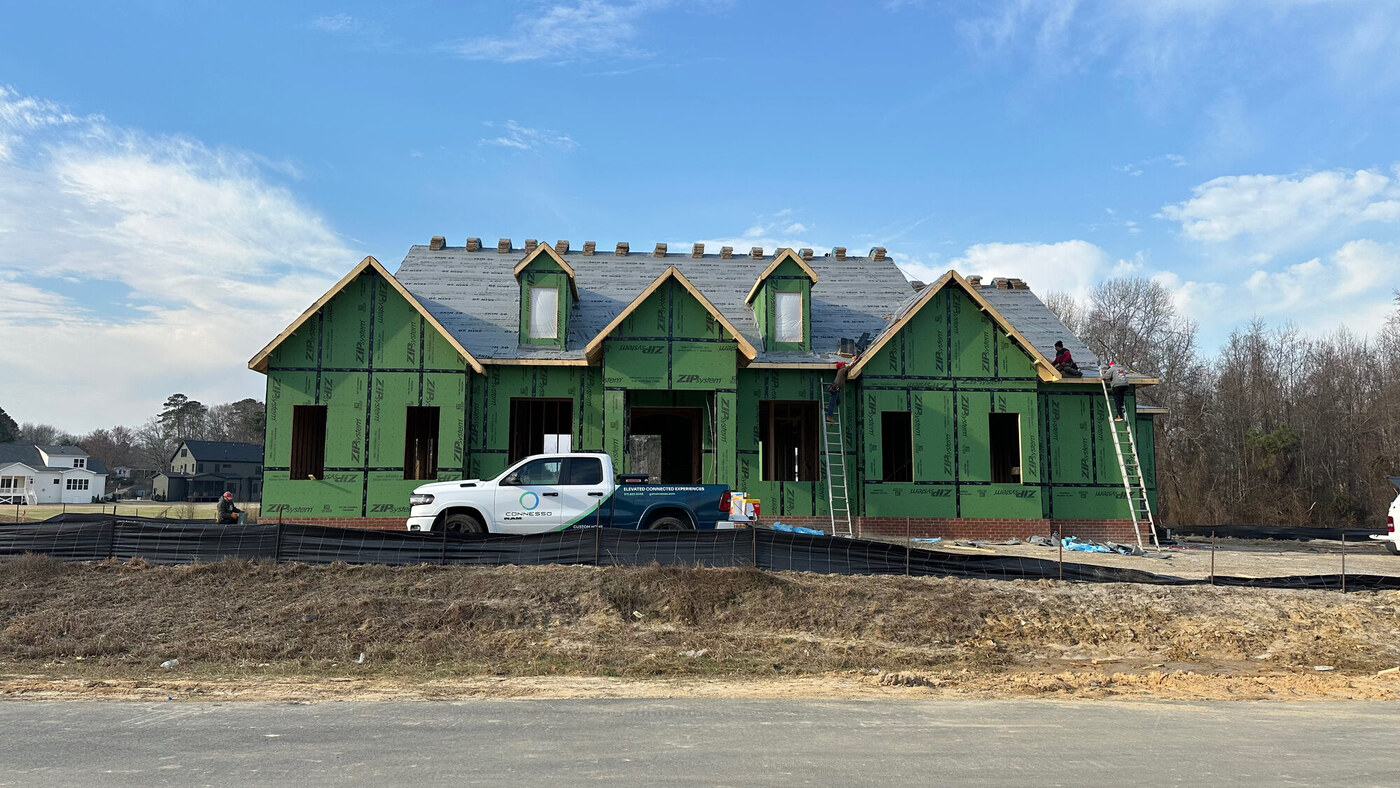 Custom home under construction with ZIP sheathing and a branded Connesso truck