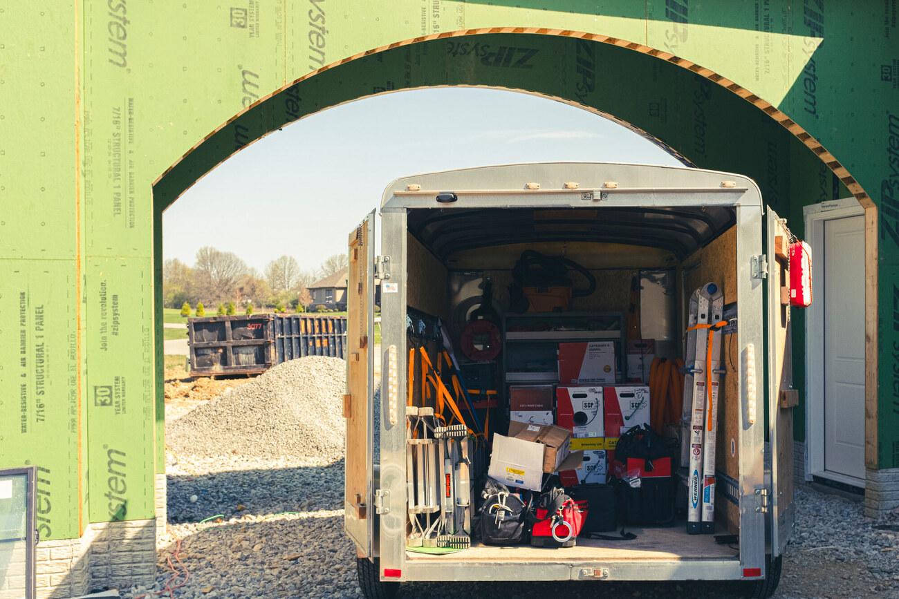 Open equipment trailer loaded with install tools at a construction site