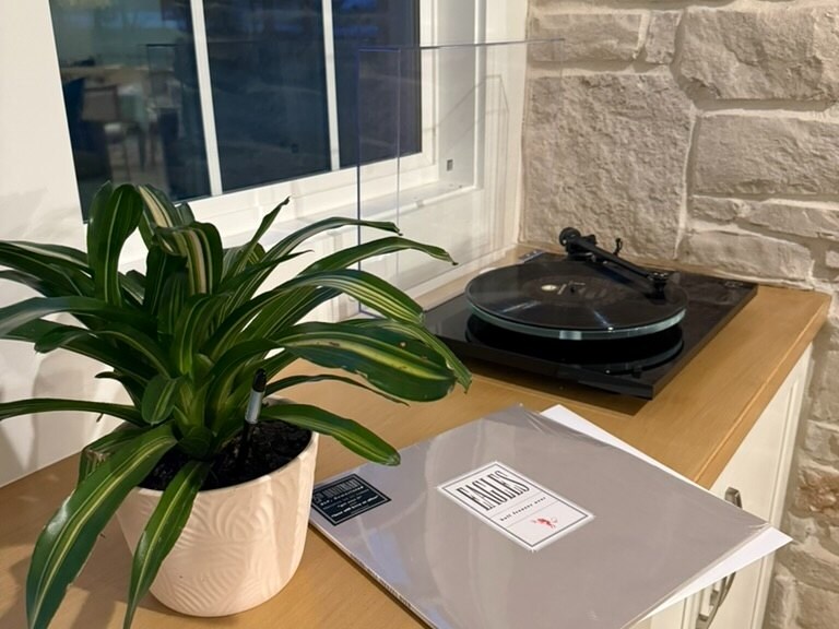 Vinyl turntable and record on a wood cabinet beside a stone wall