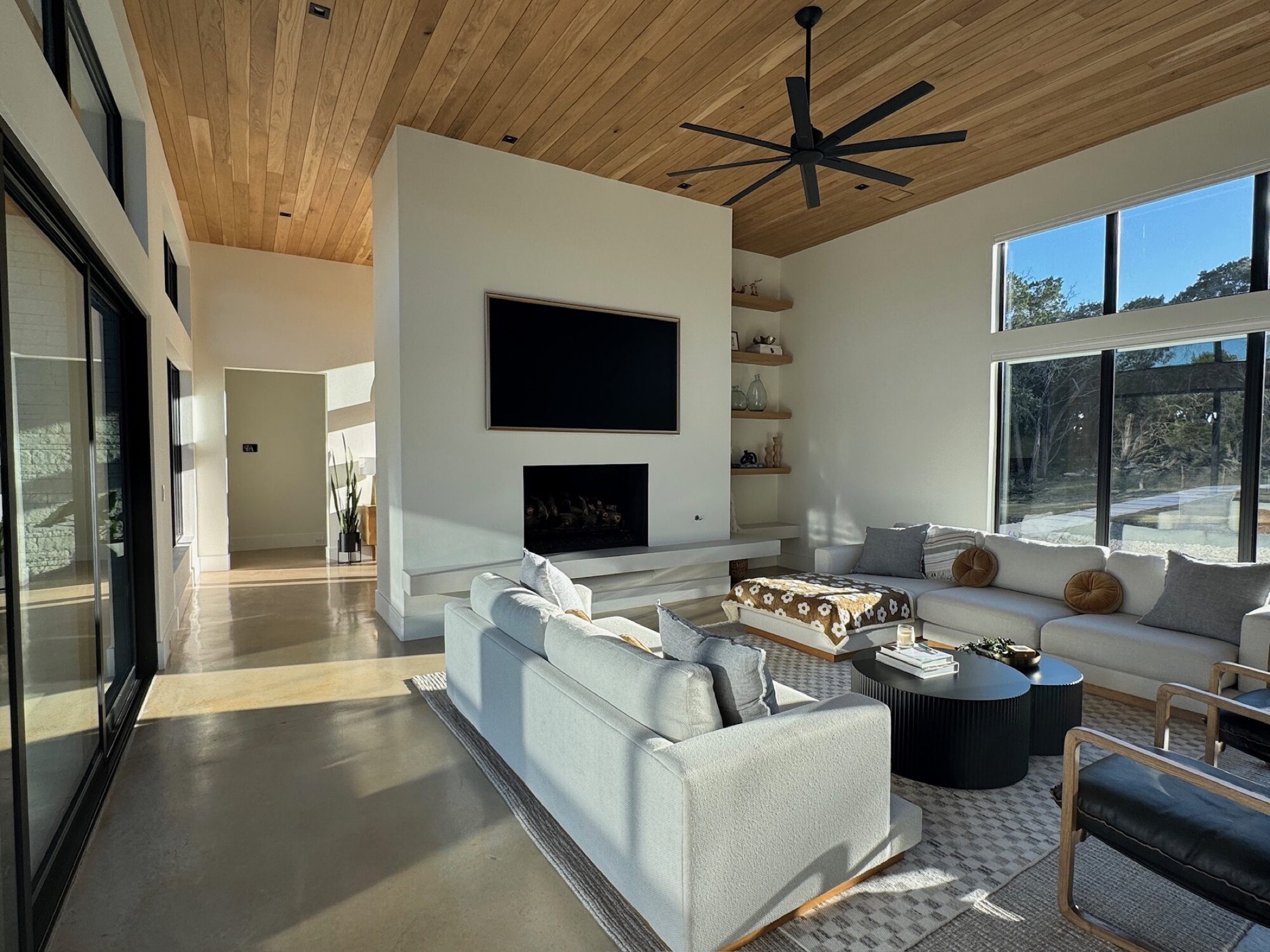 Control4 installer great room with wall-mounted TV above a linear fireplace and wood clad ceiling