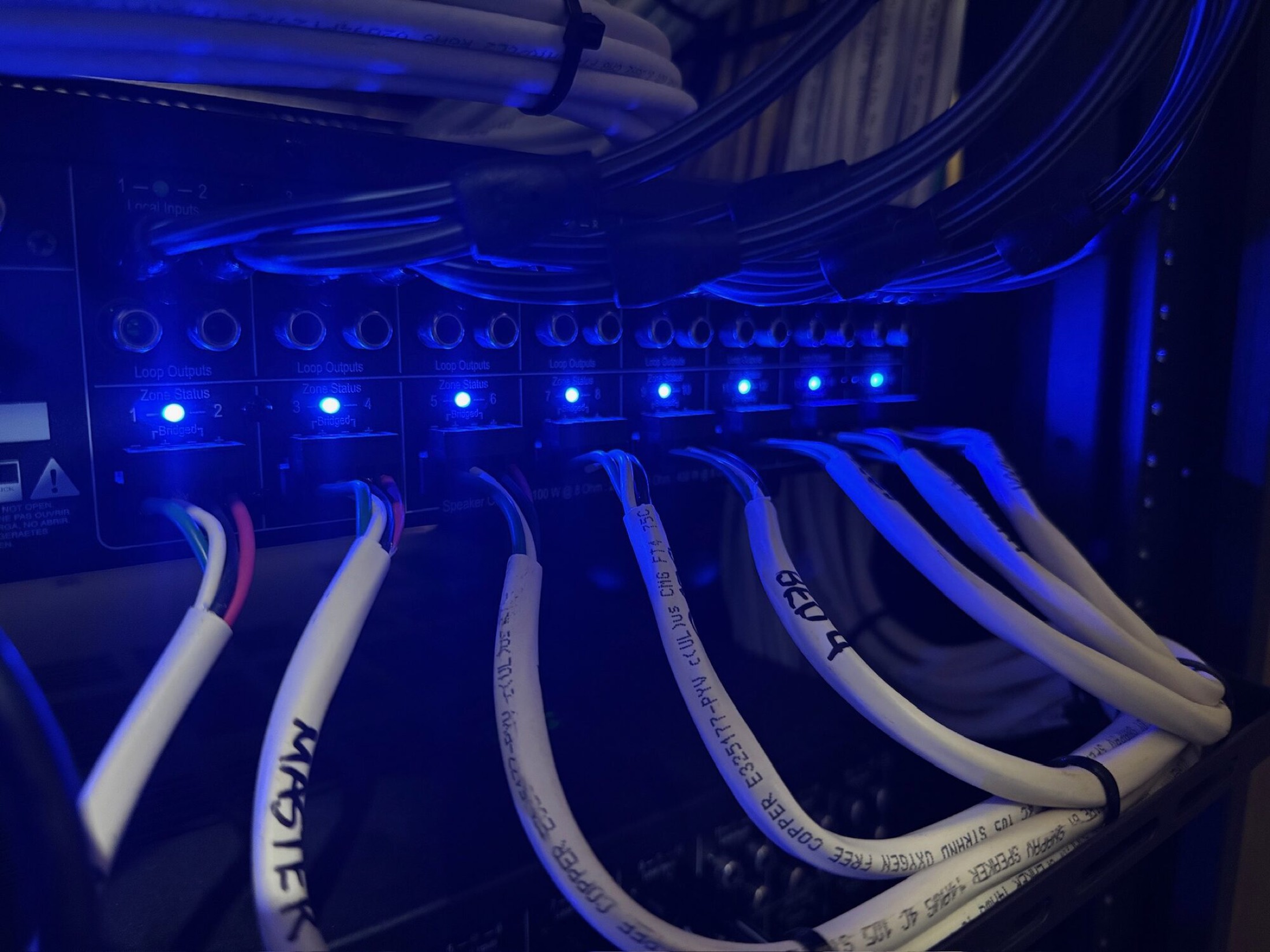 Multi-zone amplifier with labeled speaker wiring driving whole-home audio in a Control4 rack