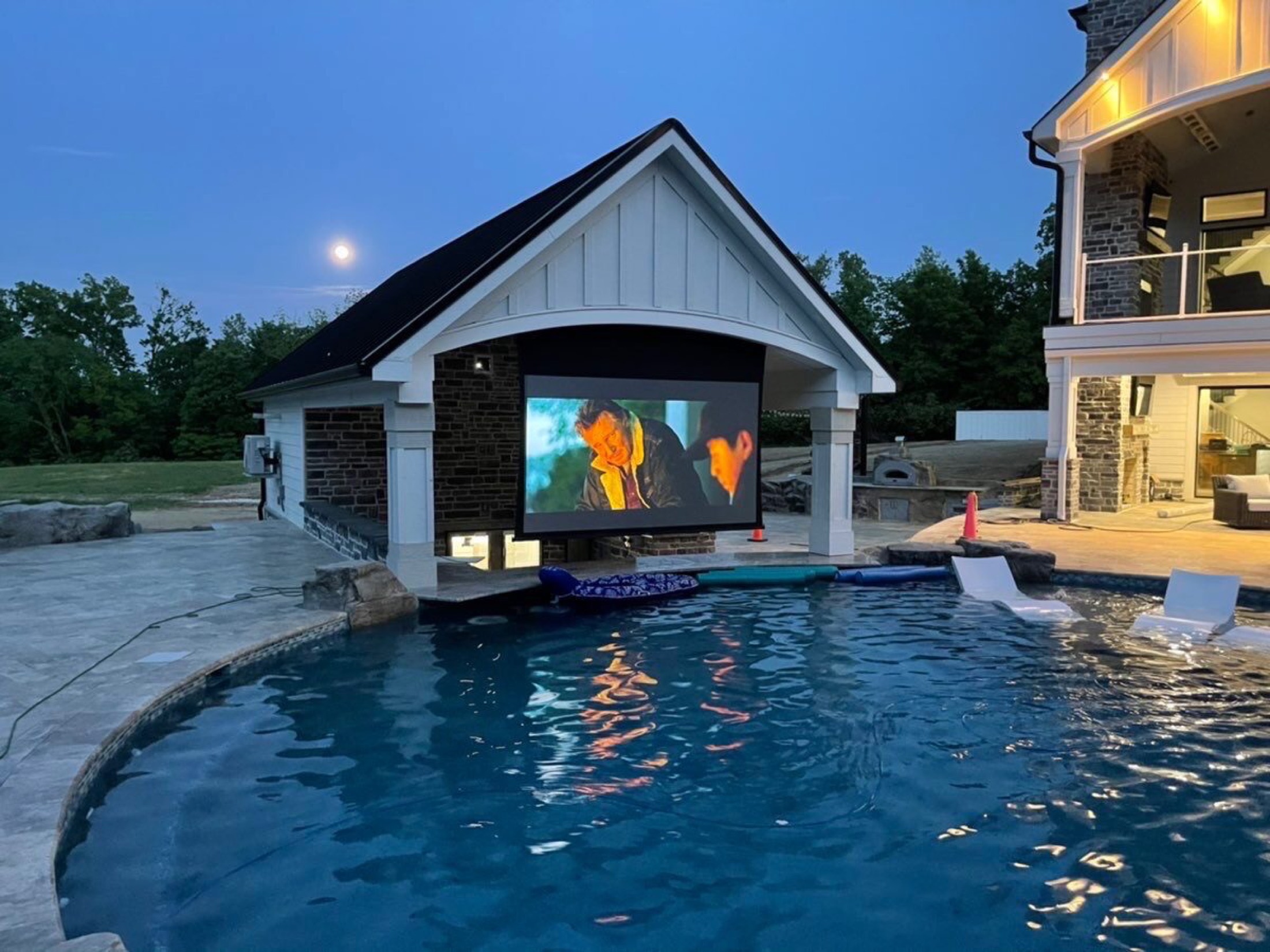 Poolside outdoor projection screen at dusk started by a Josh.ai movie time voice command