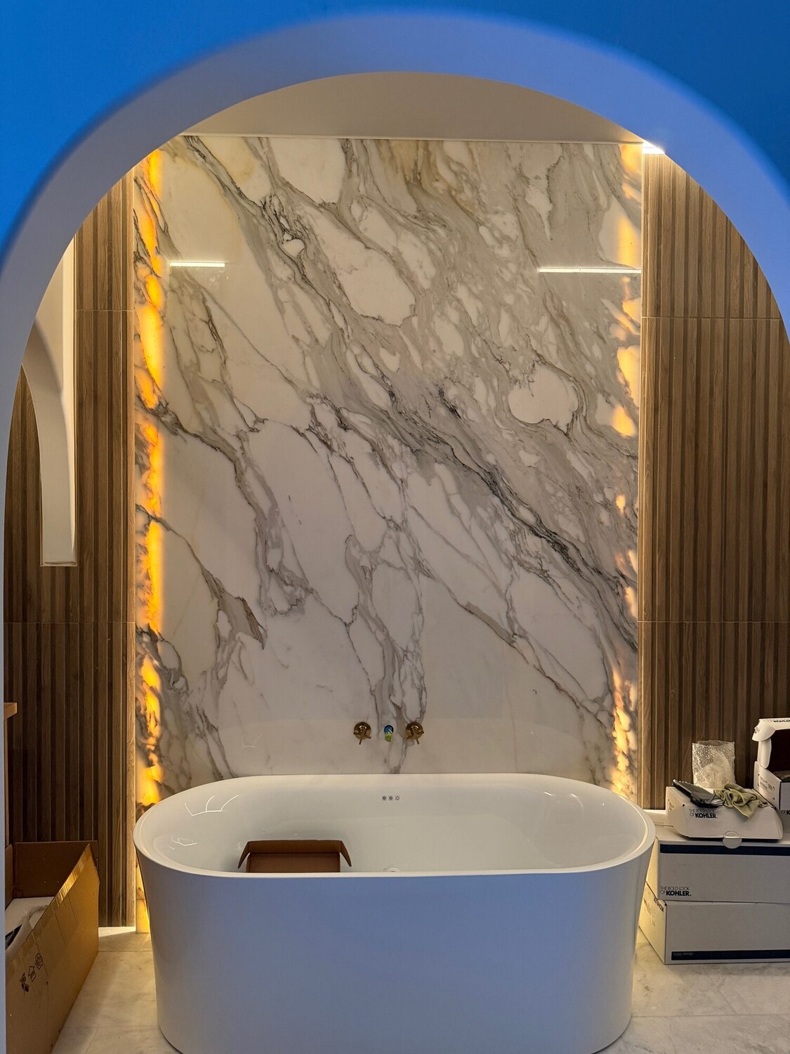 Freestanding tub against a backlit marble feature wall