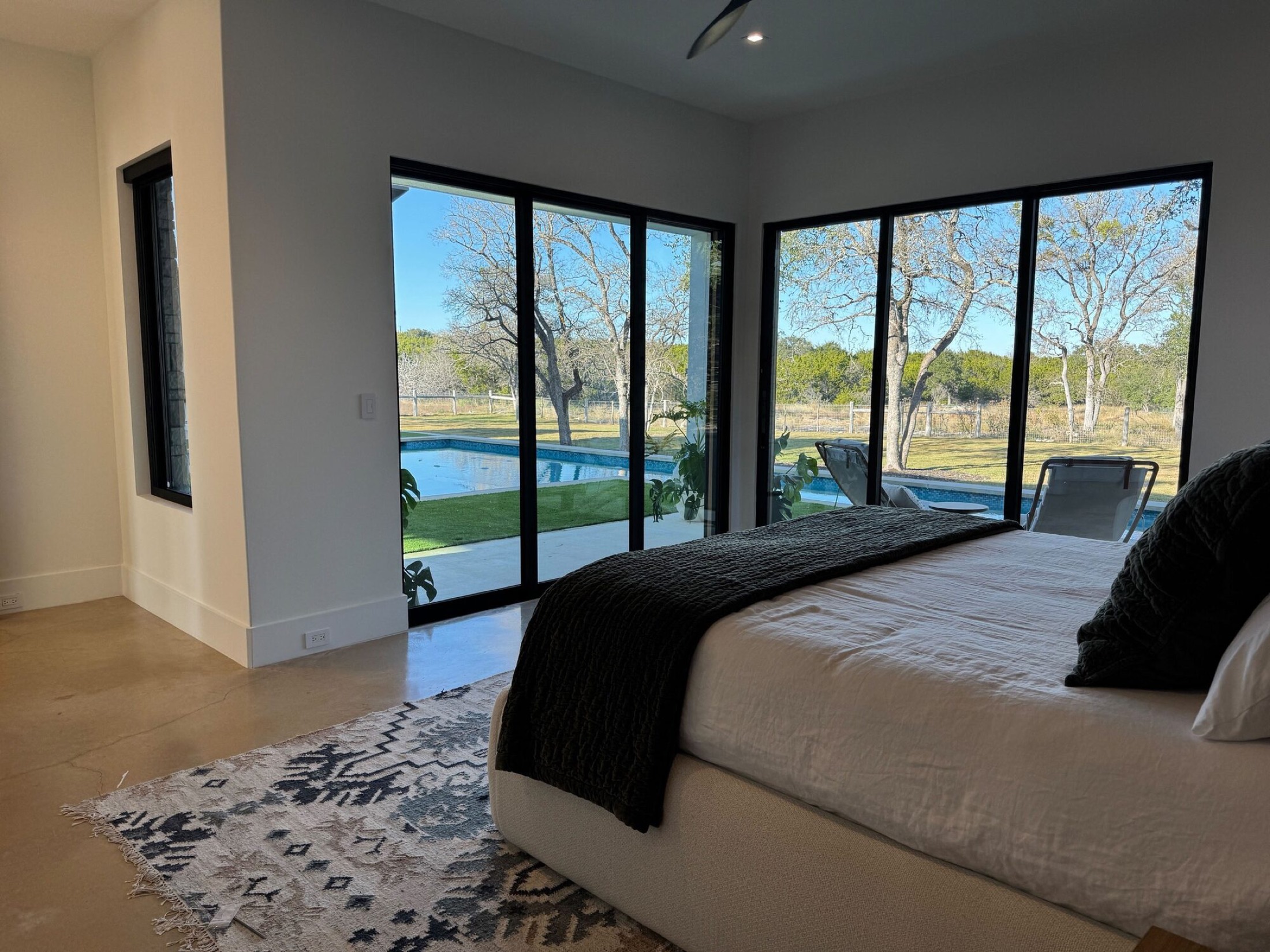 Lutron keypad on the wall of a primary bedroom with floor to ceiling sliders framing a pool view