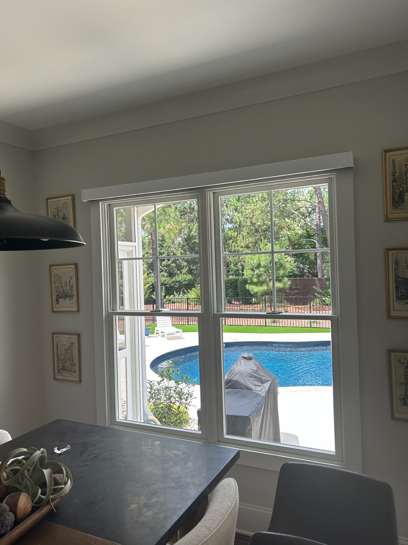 Lutron Sivoia motorized roller shade over a breakfast nook window overlooking a backyard pool