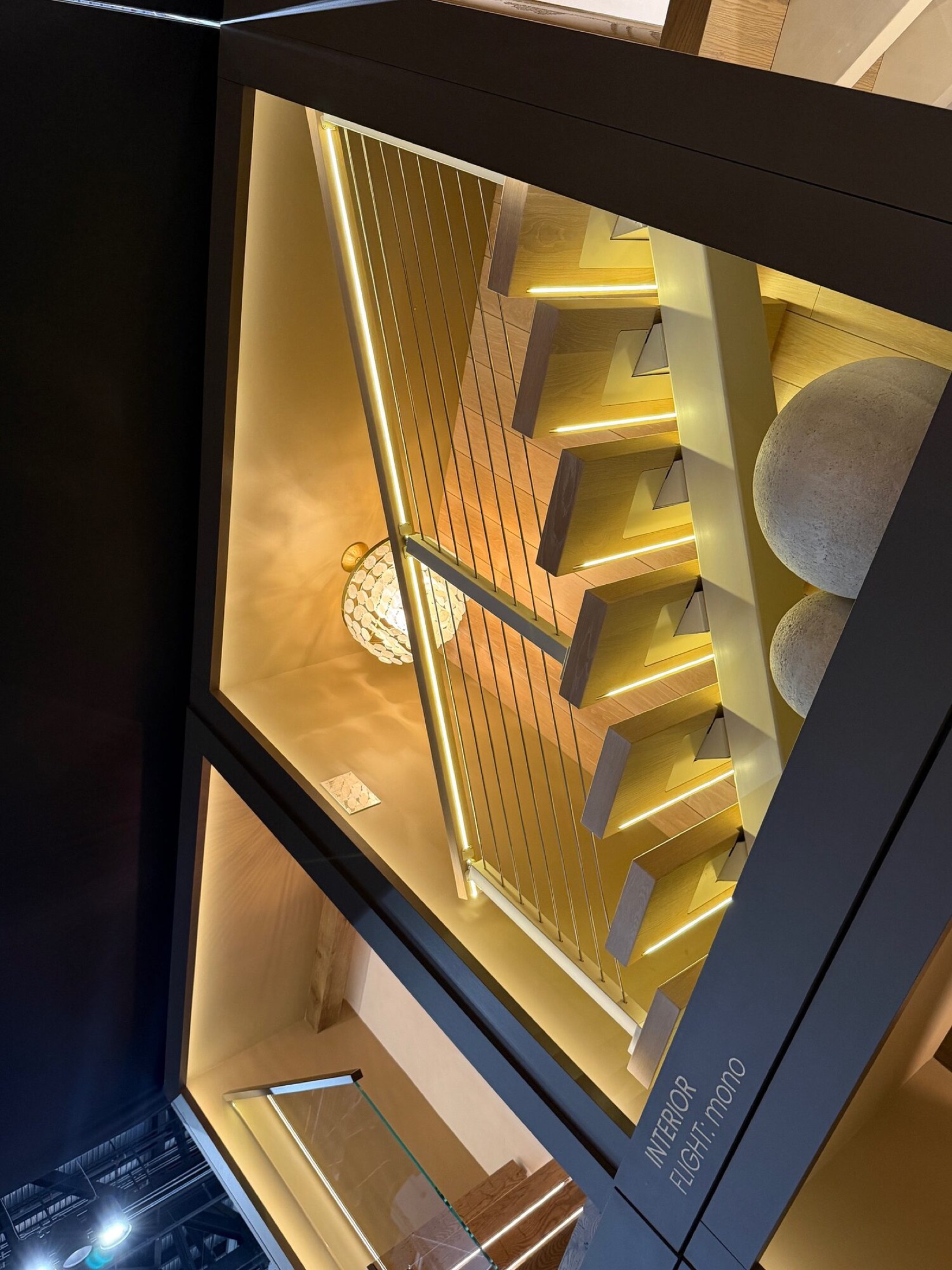 Floating wood staircase with cable railing and warm LED lighting under each tread