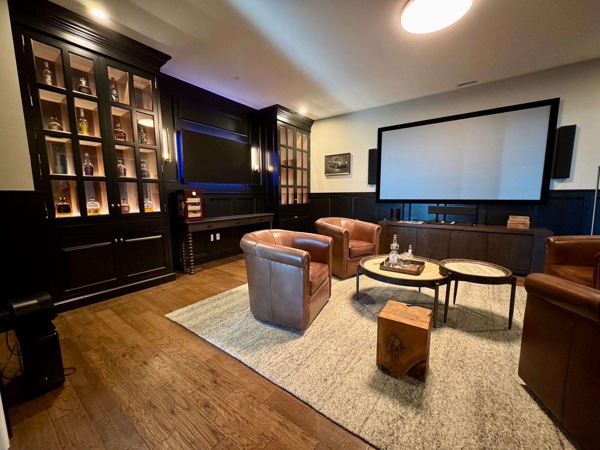 Projection screen and in-wall speakers in a downtown Columbus media lounge with leather club chairs