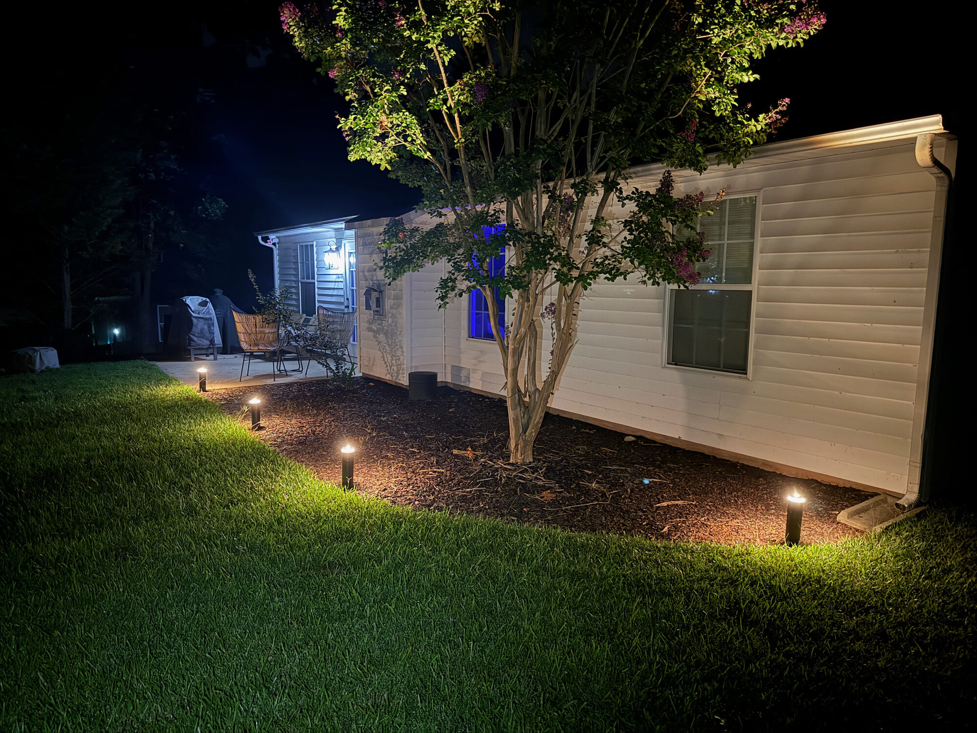 Landscape path lighting illuminating garden beds at night, Willow Spring NC