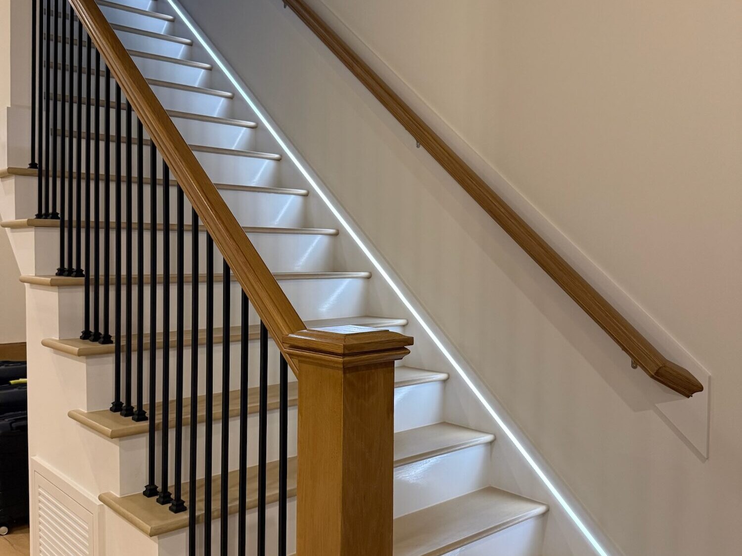 Integrated LED strip lighting running along a wood stair handrail, Cary NC