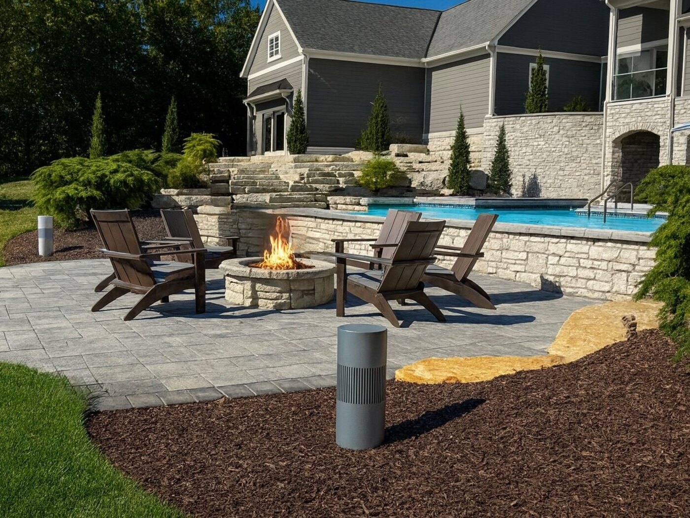 Outdoor speakers on landscape bollards beside a fire pit and pool patio, Galena OH